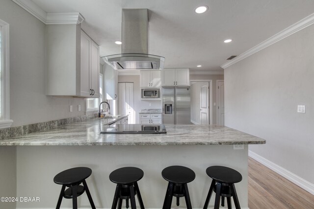 kitchen with white cabinetry, kitchen peninsula, appliances with stainless steel finishes, and island exhaust hood