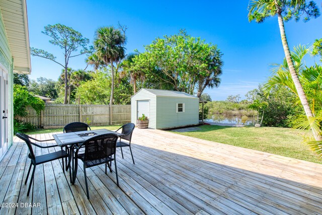 wooden deck with a shed, a lawn, and a water view