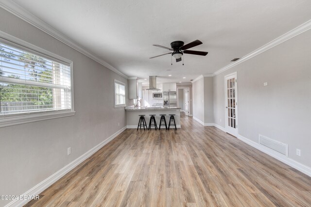 unfurnished living room with ceiling fan, french doors, light hardwood / wood-style floors, and crown molding