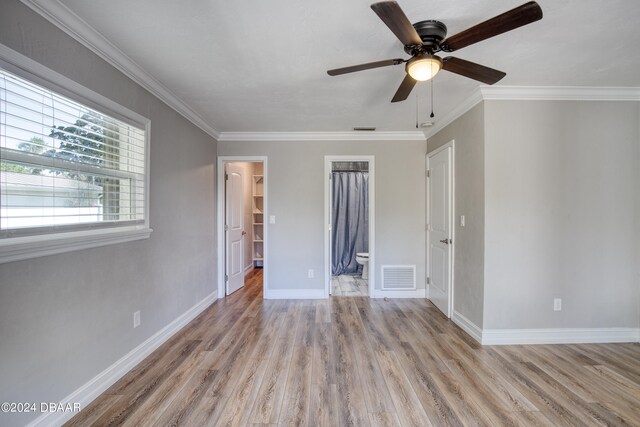 unfurnished bedroom featuring ensuite bathroom, light hardwood / wood-style flooring, ornamental molding, and ceiling fan