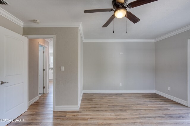 empty room with ornamental molding, light wood-type flooring, and ceiling fan