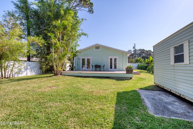 rear view of house with french doors, a wooden deck, and a yard