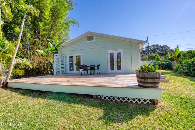 rear view of property with french doors, a wooden deck, and a lawn