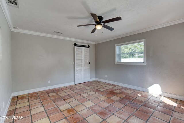 unfurnished room featuring a barn door, ceiling fan, and crown molding