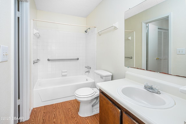 bathroom with a textured ceiling, toilet, wood finished floors, vanity, and washtub / shower combination