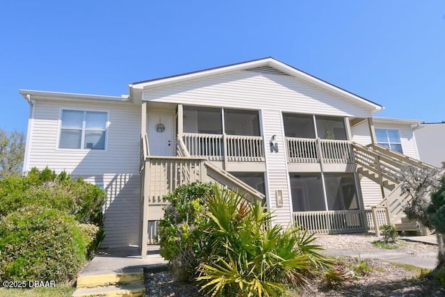 view of front of home with a sunroom and stairway