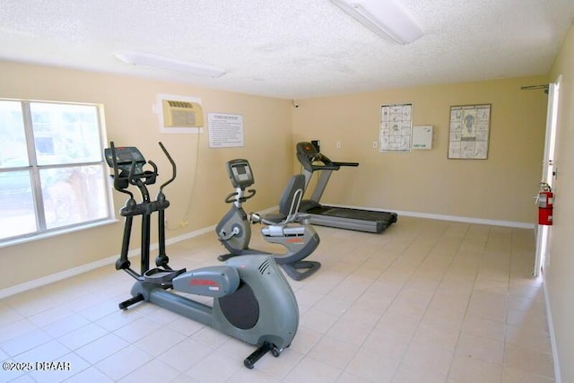 exercise area featuring baseboards, a textured ceiling, and an AC wall unit