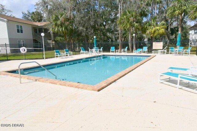 community pool with a patio area and fence