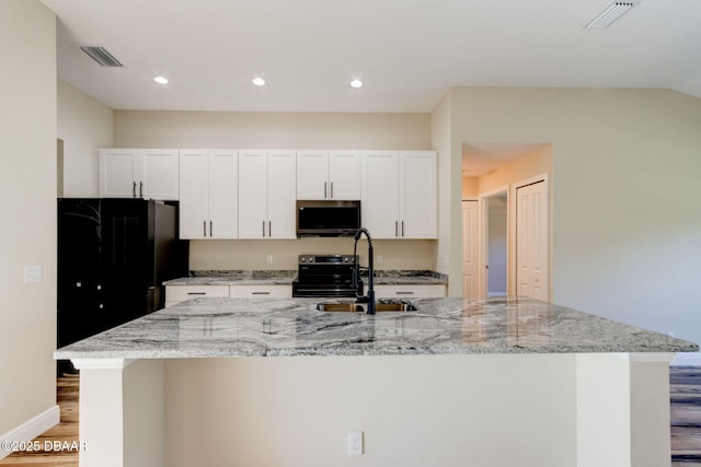 kitchen featuring white cabinets, a kitchen island with sink, range with electric stovetop, and sink