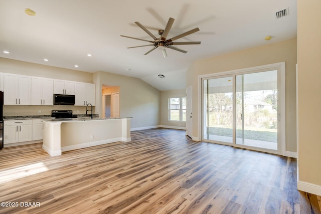 kitchen with light hardwood / wood-style flooring, sink, white cabinetry, electric range, and an island with sink