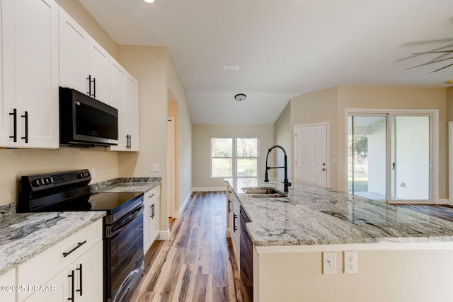 kitchen featuring light stone countertops, black appliances, white cabinetry, sink, and light hardwood / wood-style flooring