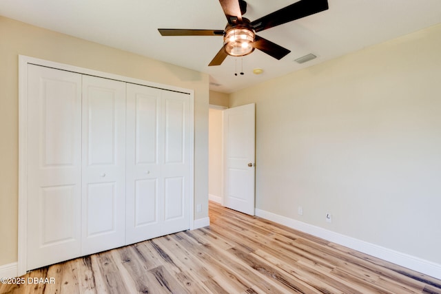 unfurnished bedroom featuring ceiling fan, light hardwood / wood-style floors, and a closet