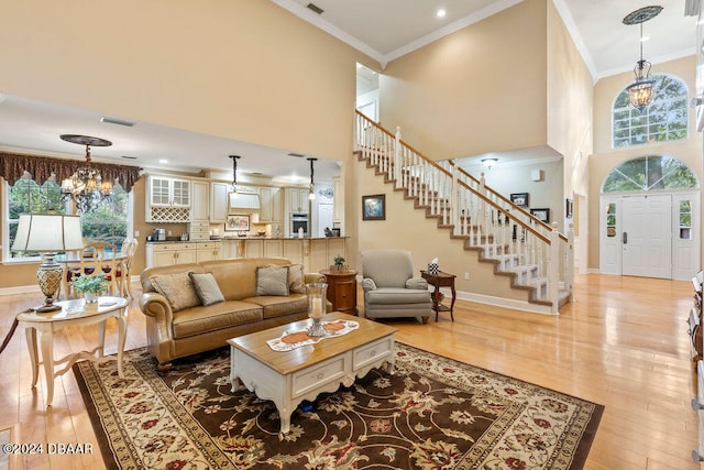 living room with plenty of natural light, a chandelier, a high ceiling, and light hardwood / wood-style flooring