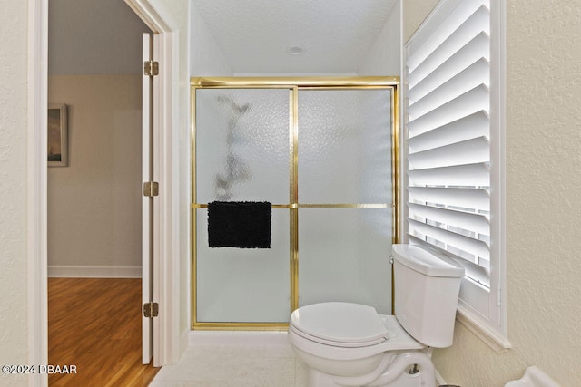 bathroom featuring toilet, hardwood / wood-style floors, a textured ceiling, and walk in shower