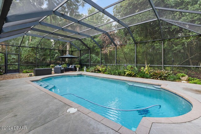 view of pool featuring glass enclosure and a patio