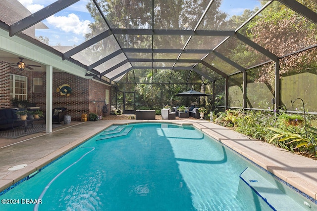 view of swimming pool featuring glass enclosure, ceiling fan, and a patio