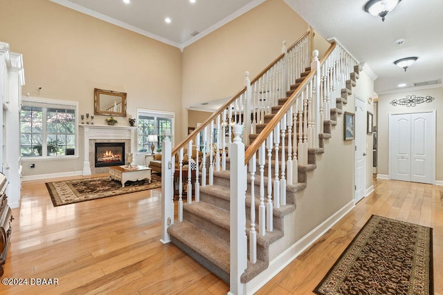 stairs featuring wood-type flooring, crown molding, and a towering ceiling