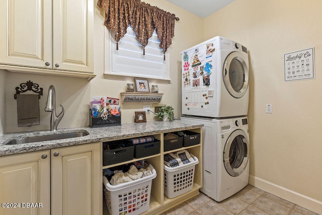 laundry area with cabinets, light tile patterned floors, sink, and stacked washer and clothes dryer