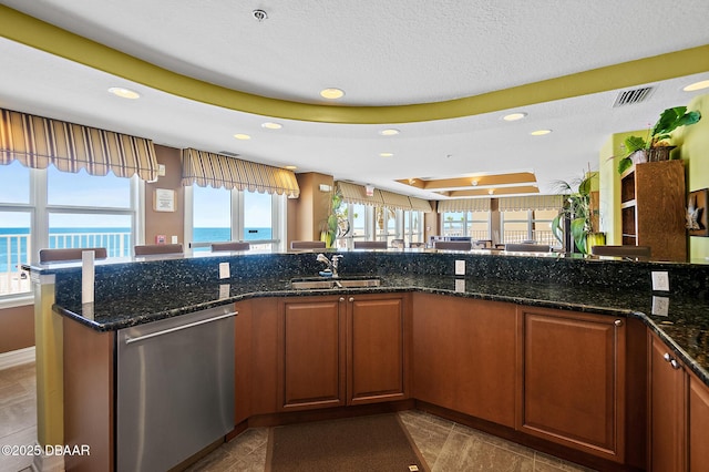 3343 S Atlantic Ave Unit 601, Daytona Beach Shores, FL 32118 - kitchen featuring dishwasher, recessed lighting, dark stone countertops, brown cabinetry, and a raised ceiling