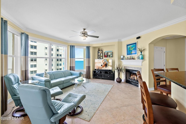 3343 S Atlantic Ave Unit 601, Daytona Beach Shores, FL 32118 - living room featuring arched walkways, a ceiling fan, a fireplace with flush hearth, plenty of natural light, and ornamental molding