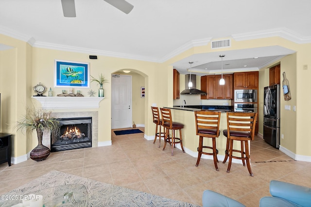 3343 S Atlantic Ave Unit 601, Daytona Beach Shores, FL 32118 - kitchen with wall chimney exhaust hood, stainless steel appliances, dark countertops, arched walkways, and brown cabinets