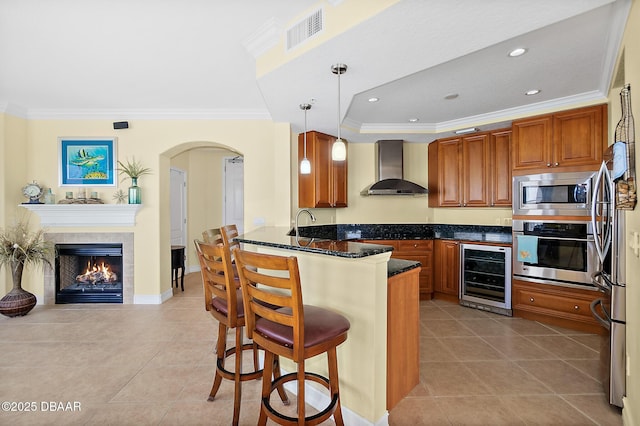 3343 S Atlantic Ave Unit 601, Daytona Beach Shores, FL 32118 - kitchen with wall chimney range hood, wine cooler, appliances with stainless steel finishes, arched walkways, and ornamental molding