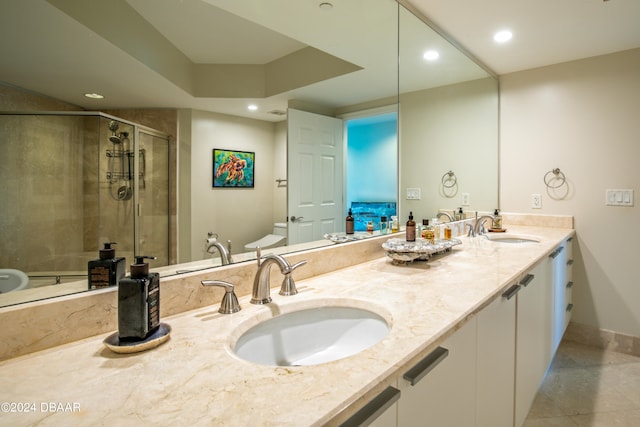 bathroom with toilet, vanity, and a shower with door