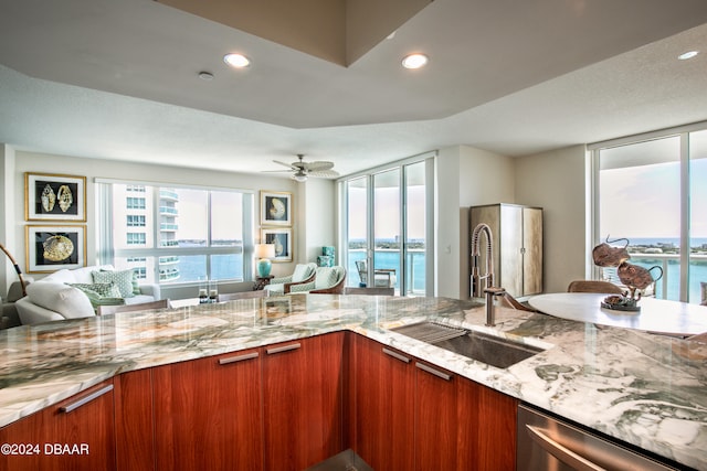 kitchen with light stone countertops, a water view, and sink