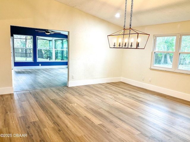 unfurnished room featuring hardwood / wood-style flooring, vaulted ceiling, and ceiling fan with notable chandelier