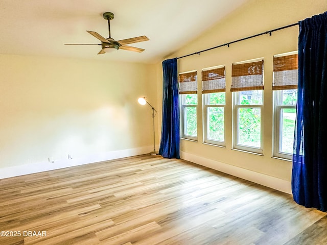 unfurnished room featuring ceiling fan, a healthy amount of sunlight, vaulted ceiling, and light wood-type flooring