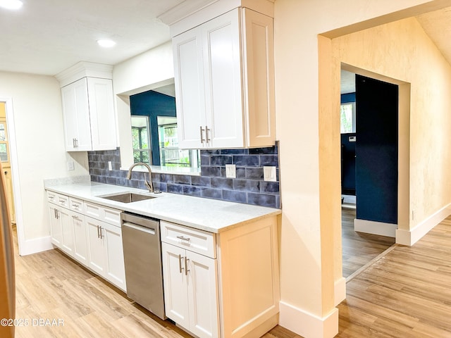 kitchen featuring sink, white cabinetry, backsplash, stainless steel dishwasher, and light wood-type flooring