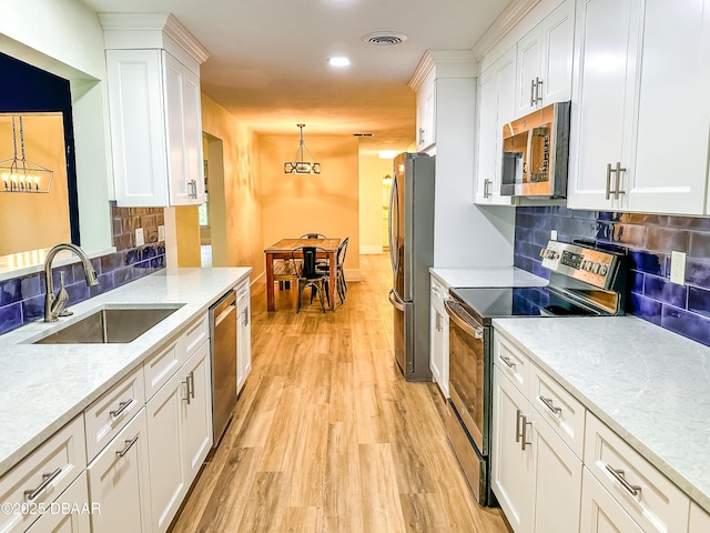 kitchen featuring hanging light fixtures, appliances with stainless steel finishes, sink, and white cabinets