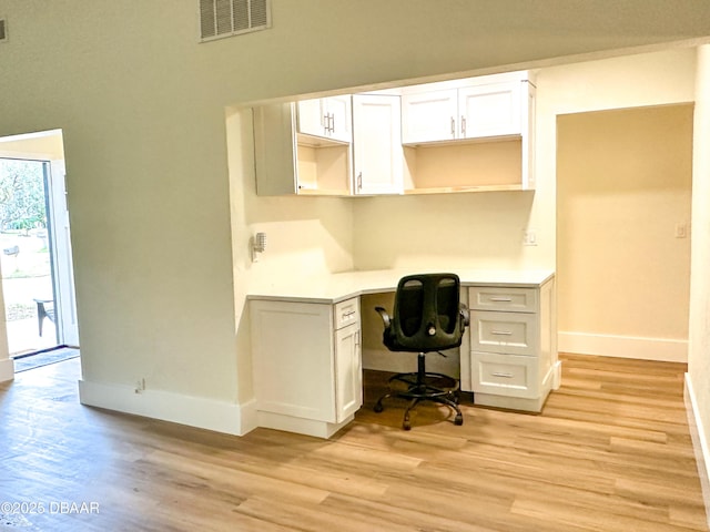 home office featuring built in desk and light hardwood / wood-style floors