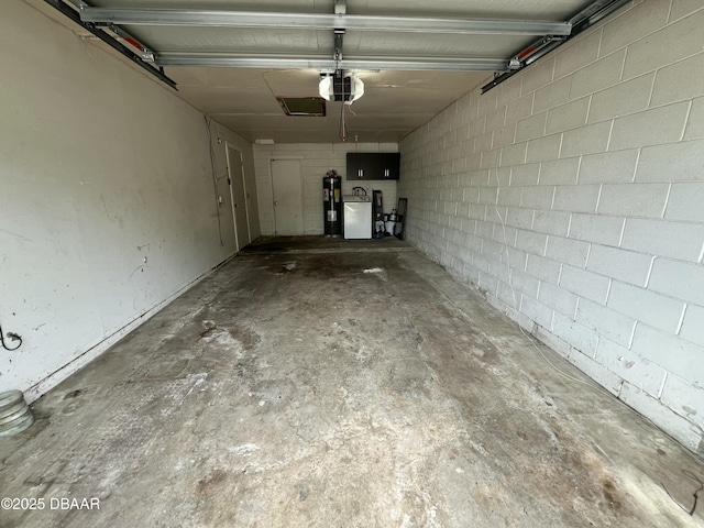 garage with water heater, washing machine and dryer, concrete block wall, and a garage door opener