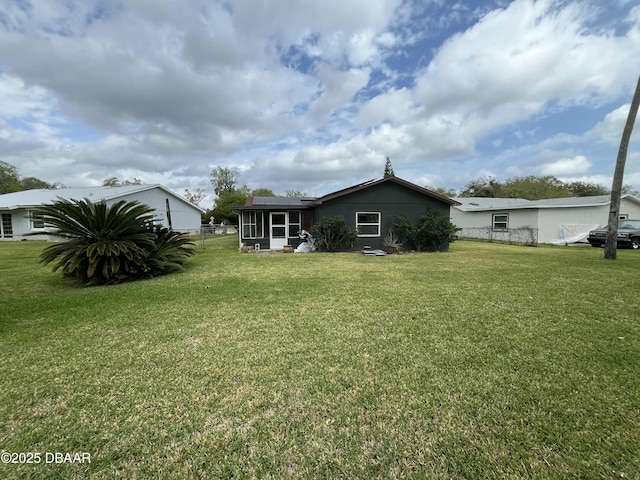 back of property featuring a yard, fence, and a sunroom