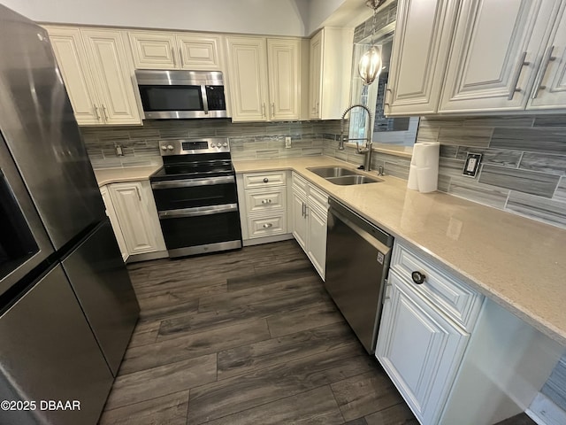 kitchen with light countertops, decorative backsplash, appliances with stainless steel finishes, white cabinets, and a sink