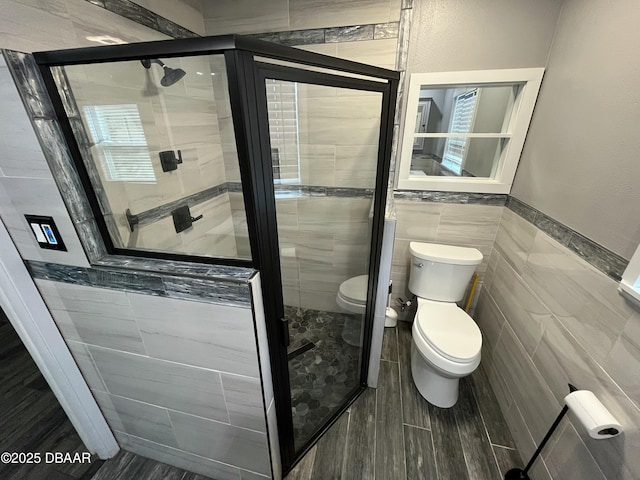 bathroom featuring toilet, a shower stall, and tile walls