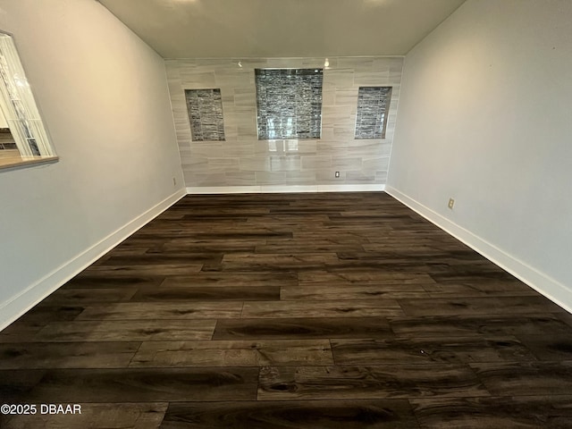 unfurnished room with dark wood-type flooring and baseboards