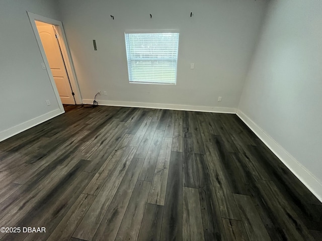 spare room with baseboards and dark wood finished floors