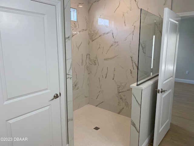 bathroom with wood-type flooring and tiled shower