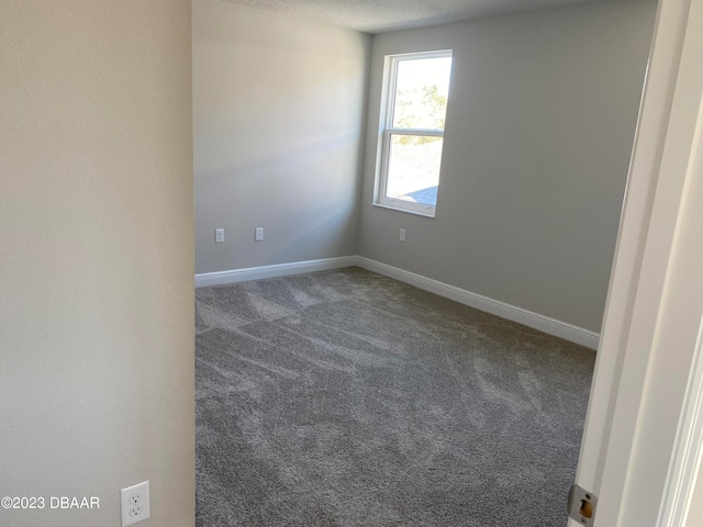 empty room featuring a textured ceiling and dark carpet