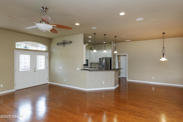 6065 Spruce Point Cir, Port Orange, FL 32128 - kitchen with stainless steel fridge with ice dispenser, wood finished floors, dark countertops, ceiling fan, and backsplash