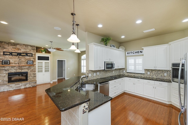 6065 Spruce Point Cir, Port Orange, FL 32128 - kitchen featuring appliances with stainless steel finishes, a fireplace, hardwood / wood-style flooring, decorative backsplash, and recessed lighting