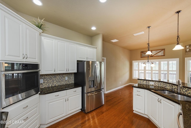 6065 Spruce Point Cir, Port Orange, FL 32128 - kitchen with appliances with stainless steel finishes, decorative backsplash, white cabinets, dark wood finished floors, and recessed lighting