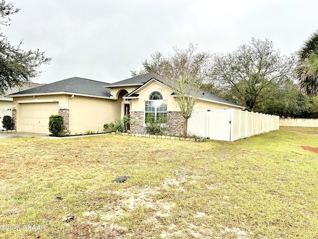 view of front of property featuring stone siding, an attached garage, fence, and a front yard