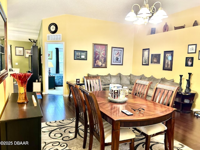 dining space featuring visible vents, a chandelier, and wood finished floors