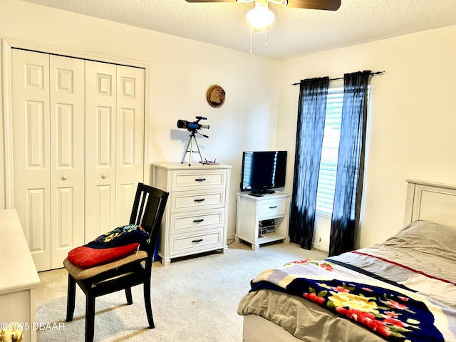 bedroom featuring a closet, light colored carpet, ceiling fan, and a textured ceiling