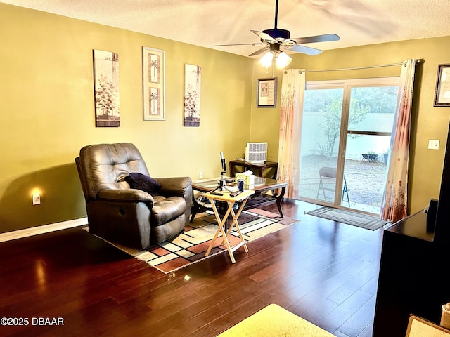 living area with a ceiling fan, a textured ceiling, baseboards, and wood finished floors