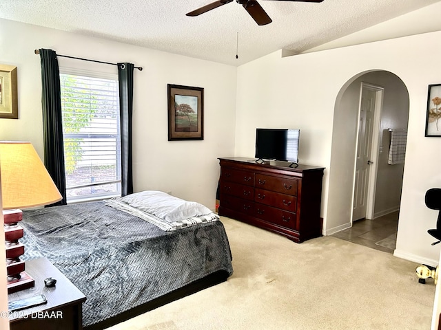 bedroom featuring arched walkways, ceiling fan, a textured ceiling, lofted ceiling, and light colored carpet