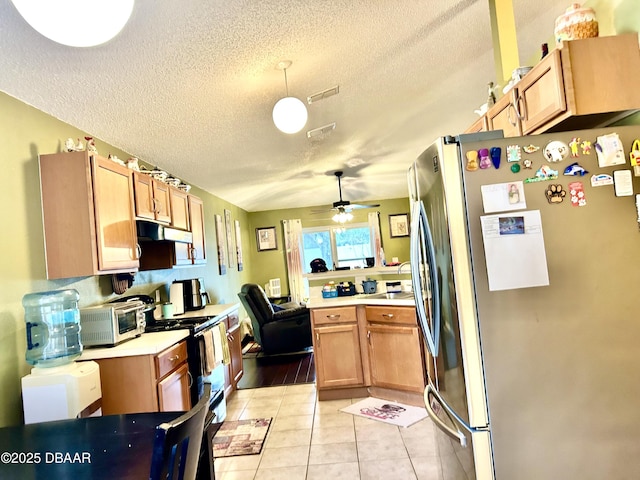 kitchen with light countertops, hanging light fixtures, electric range, freestanding refrigerator, and under cabinet range hood